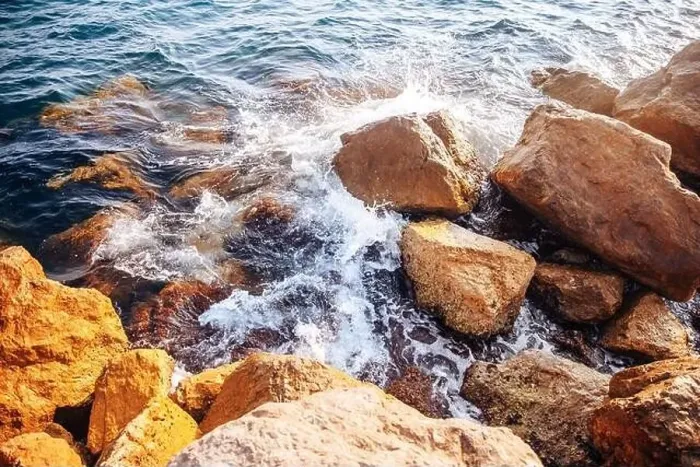 Framed Print : Stormy sea with waves and splashes breaks on sharp stones, warm day, light of sun Framed Print : Stormy sea with waves and splashes breaks on sharp stones, warm day, light of sun