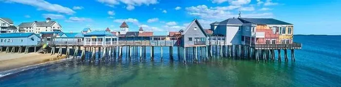 Framed Print : Stunning side profile of entire old wood pier in Maine covered in shops and buildings on beach Framed Print : Stunning side profile of entire old wood pier in Maine covered in shops and buildings on beach