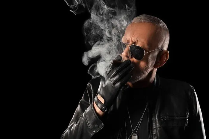 Framed Print : Stylish old man in leather jacket smoking cigar on black background