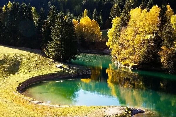 Sunny autumn view of Soraga lake in Soraga di Fassa village, Province of Trento, Italy, Dolomite Alps. Landscape photography