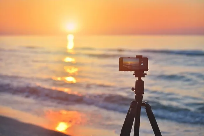 Framed Print : Sunrise over the sea coast. Fireball of the sun above the horizon in a colorful orange sky. Smartphone camera on a tripod in the foreground Framed Print : Sunrise over the sea coast. Fireball of the sun above the horizon in a colorful orange sky. Smartphone camera on a tripod in the foreground