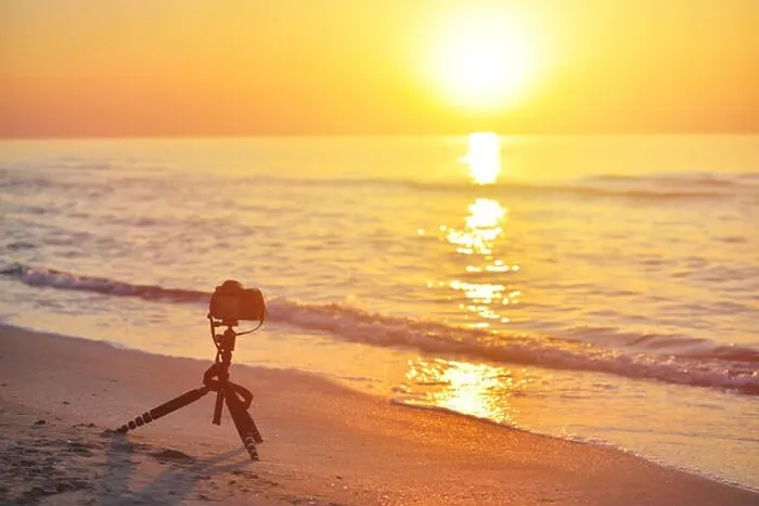 Framed Print : Sunrise over the sea coast. Fireball of the sun above the horizon in a colorful orange sky. DSLR camera on a tripod in the foreground Framed Print : Sunrise over the sea coast. Fireball of the sun above the horizon in a colorful orange sky. DSLR camera on a tripod in the foreground