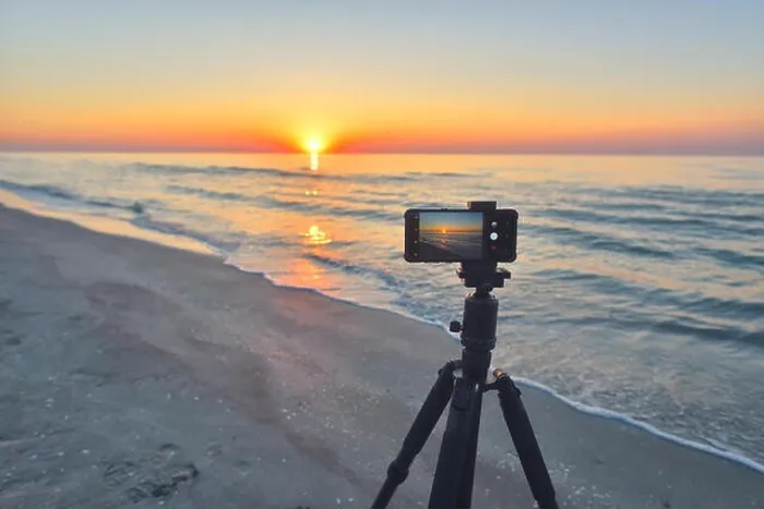 Framed Print : Sunrise over the sea coast. Fireball of the sun above the horizon in a colorful orange sky. Smartphone camera on a tripod in the foreground Framed Print : Sunrise over the sea coast. Fireball of the sun above the horizon in a colorful orange sky. Smartphone camera on a tripod in the foreground