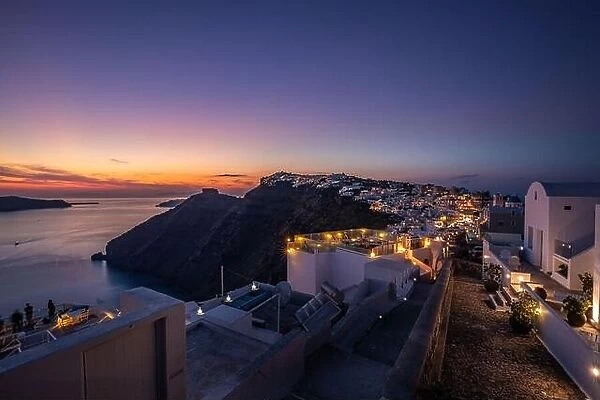 Sunset on the famous Greek resort Fira, Greece, Europe. Traveling concept background. Romantic Santorini island during sunset, amazing view, lights