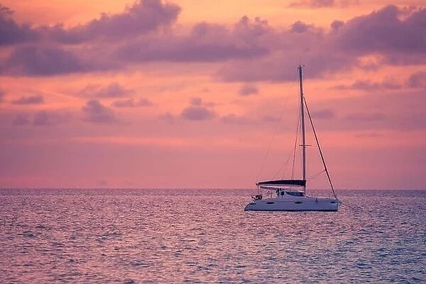 Sunset views at the sea with a yacht or silhouette of catamaran. Luxury travel and tourism vacation. Summer recreational background, seascape