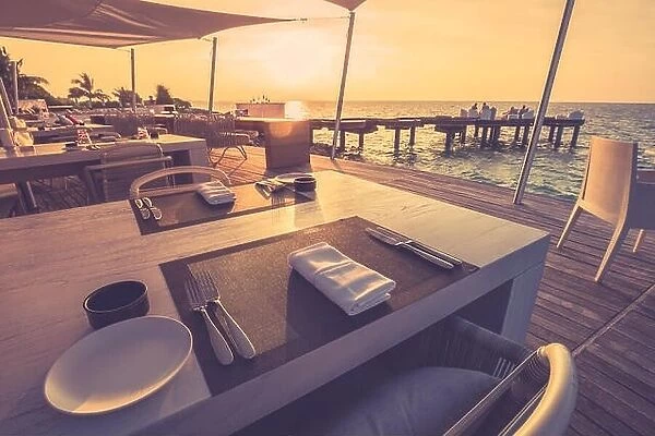 Table dinner setting at the beach on twilight time in tropical shoreline, relaxing mood
