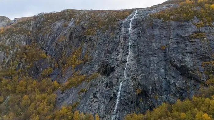Framed Print : A tall, narrow waterfall cascading down a rugged, rocky cliff surrounded by autumn foliage Framed Print : A tall, narrow waterfall cascading down a rugged, rocky cliff surrounded by autumn foliage