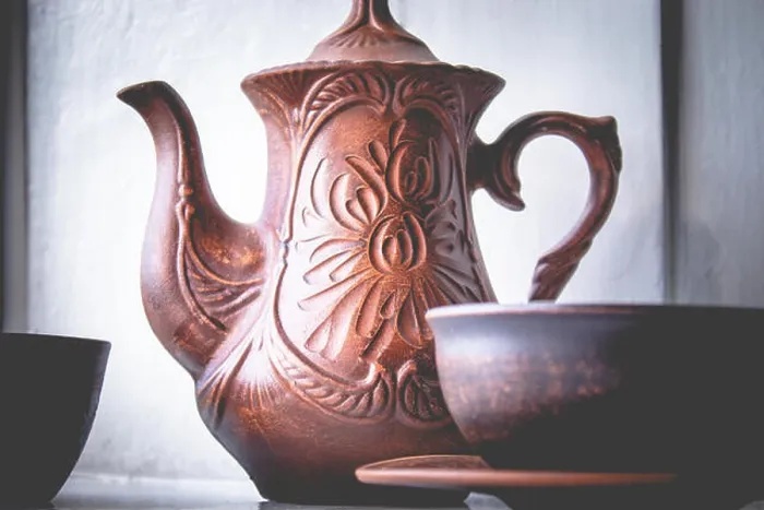 Framed Print : A teapot and a cup of clay are standing near the window. Close-up Framed Print : A teapot and a cup of clay are standing near the window. Close-up