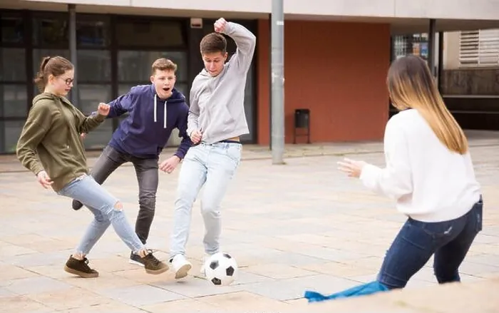 Framed Print : Teen friends spending time together outdoors playing with ball on square near school Framed Print : Teen friends spending time together outdoors playing with ball on square near school