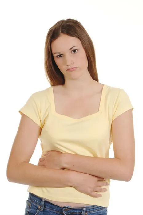 Framed Print : a teenage girl holding her stomach looking in pain Framed Print : a teenage girl holding her stomach looking in pain