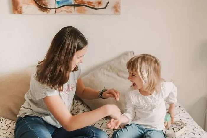 Framed Print : Teenage girl tickling little sister on bed Framed Print : Teenage girl tickling little sister on bed