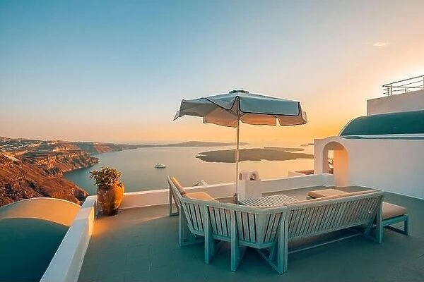 Terrace at sunset in Santorini Island, Greece. Beautiful resort caldera view sunset sky. Relax vibes, umbrella and chairs, table. Summer vacation