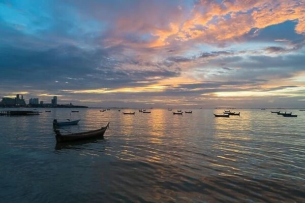 Many Thai fishing boat mooring in sea near Pattaya, Thailand at sunset