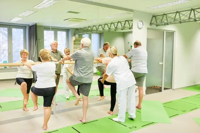 Framed Print : Therapist cares for seniors in physiotherapy on the ballet bar as a fall prevention Framed Print : Therapist cares for seniors in physiotherapy on the ballet bar as a fall prevention