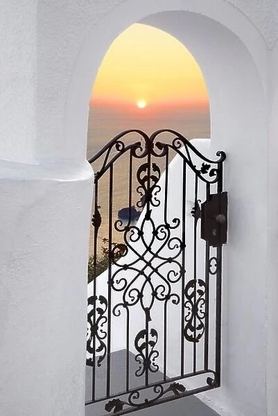 Thira (capital city of Santorini) - doorway with white walls and the sunset in the background, Santorini Island, Greece