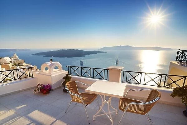 Thira (capital city of Santorini) - terrace with a background view to the sea and sun on the sky, Santorini Island, Greece