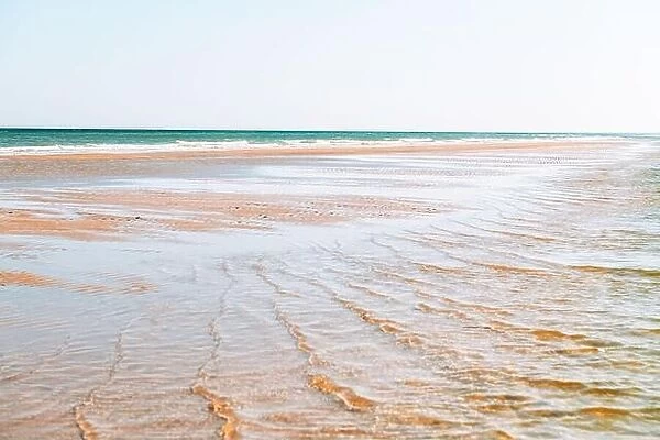 Tide waves on tropical beach sand and blue ocean water. Beauty sea texture. Vacations background