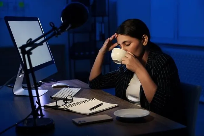 Framed Print : Tired overworked businesswoman drinking coffee at night in office