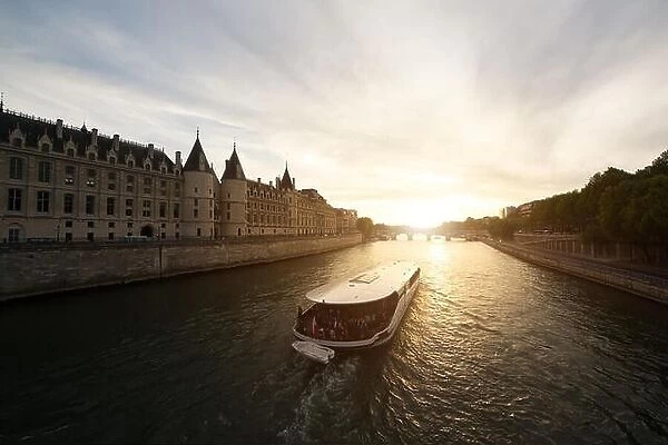 Tourist boat tour on Seine river with beautiful sunset in Paris. Cruise ship sightseeing along river in Paris, France