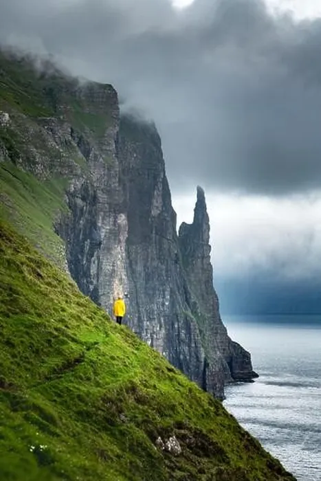 Framed Print : Tourist in yellow jacket looks at Witches Finger cliffs from Trollkonufingur viewpoint. Vagar island, Faroe Islands, Denmark Framed Print : Tourist in yellow jacket looks at Witches Finger cliffs from Trollkonufingur viewpoint. Vagar island, Faroe Islands, Denmark