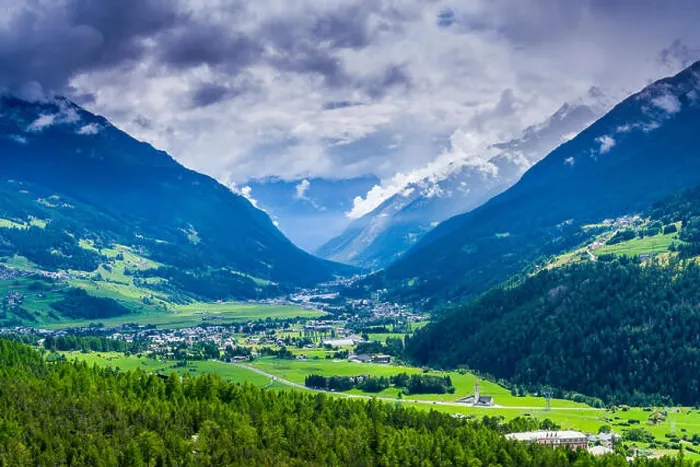 Framed Print : The town is located at the bottom of a narrow valley, surrounded by mountains and forest, dark clouds at the sky Framed Print : The town is located at the bottom of a narrow valley, surrounded by mountains and forest, dark clouds at the sky