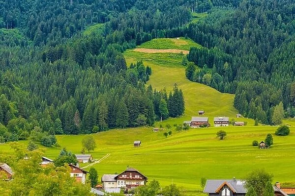 Traditional Alpine house, wooden cabin. Alps landscape, green grass, lawn and beautiful alpine scenery