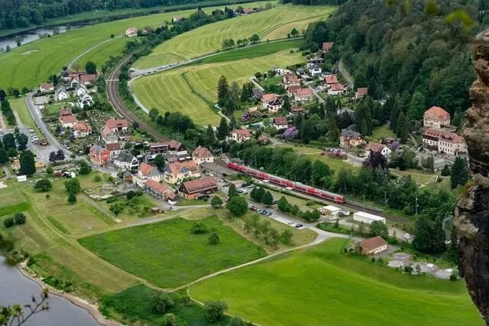 Framed Print : A train is traveling through a small town with houses and a river in the background Framed Print : A train is traveling through a small town with houses and a river in the background
