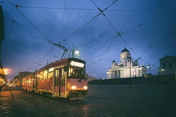 Tram passing Helsinki Senate Square during sunset with Helsinki Cathedral in the background at Finland
