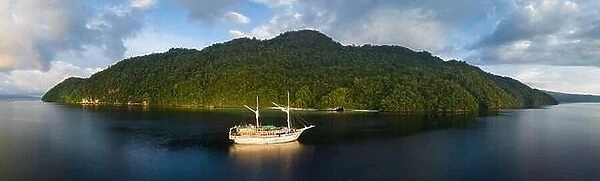 A tranquil sunrise illuminates a Phinisi schooner on the Pacific Ocean not far from Fak Fak, West Papua, Indonesia