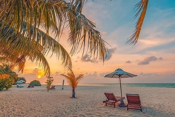 Tranquil tropical sunset landscape, couple sun beds, loungers, umbrella under palm leaves colorful twilight sky. Romance love honeymoon concept
