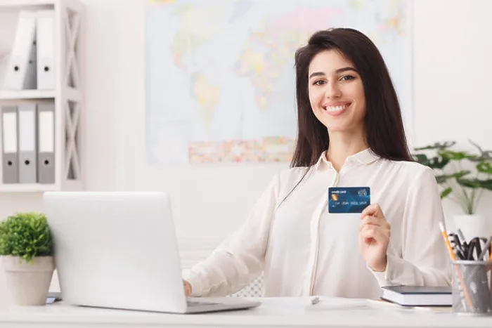 Framed Print : Travel agency. Woman showing credit card, looking at camera Framed Print : Travel agency. Woman showing credit card, looking at camera