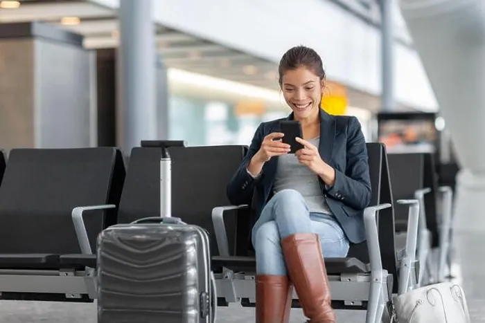 Framed Print : Travel airport woman using mobile phone waiting in lounge with hand luggage Framed Print : Travel airport woman using mobile phone waiting in lounge with hand luggage