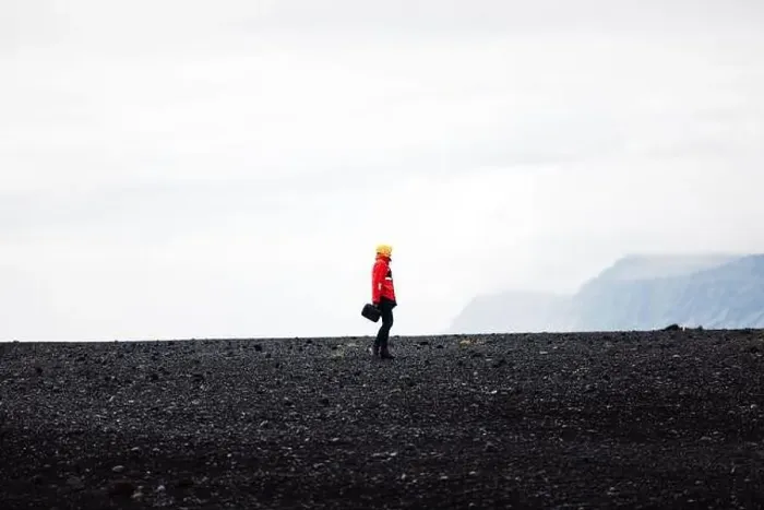 Framed Print : Traveler in a red jacket standing on a black sand beach in Iceland Framed Print : Traveler in a red jacket standing on a black sand beach in Iceland