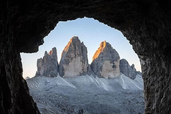 Tre Cime Di Lavaredo peaks in incredible orange sunset light. View from the cave in mountain against Three peaks of Lavaredo, Dolomite Alps, Italy