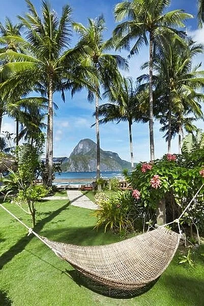 Tropical garden in front of the sea, hammock between a palm trees, El-Nido, Philippines