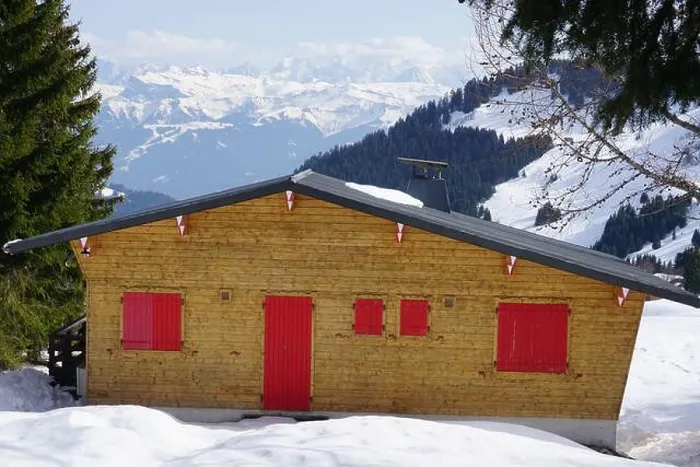 Framed Print : typical wooden chalet with red shutters in the Alps, France on the ski slopes with a panorama Framed Print : typical wooden chalet with red shutters in the Alps, France on the ski slopes with a panorama