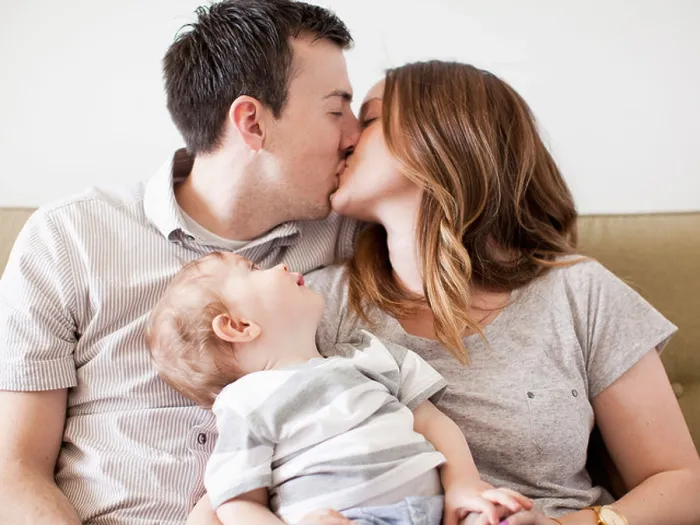 Framed Print : USA, Utah, Salt Lake City, Young couple kissing with baby boy (6-11 months) on their lap
