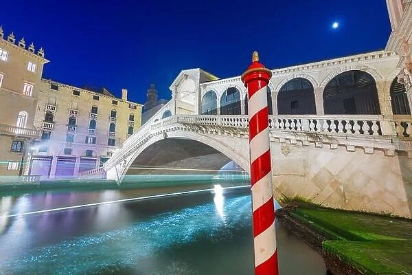 Venice, Italy with light trails on the Grand Canal passing under the Rialto Bridge at night