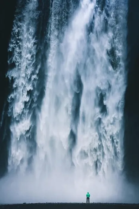 Framed Print : Vertical panorama view of hiker in colorful rain jacket standing in front of gigantic Skogafoss waterfall Framed Print : Vertical panorama view of hiker in colorful rain jacket standing in front of gigantic Skogafoss waterfall