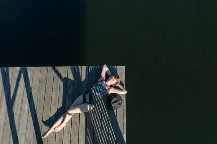 Framed Print : Top view of beautiful Woman in black swimsuit and hat lying down on wooden pier of lake on clear blue sky Framed Print : Top view of beautiful Woman in black swimsuit and hat lying down on wooden pier of lake on clear blue sky