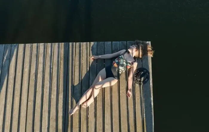 Framed Print : Top view of beautiful Woman in black swimsuit and hat lying down on wooden pier of lake on clear blue sky Framed Print : Top view of beautiful Woman in black swimsuit and hat lying down on wooden pier of lake on clear blue sky