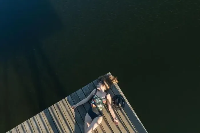 Framed Print : Top view of beautiful Woman in black swimsuit and hat lying down on wooden pier of lake on clear blue sky Framed Print : Top view of beautiful Woman in black swimsuit and hat lying down on wooden pier of lake on clear blue sky