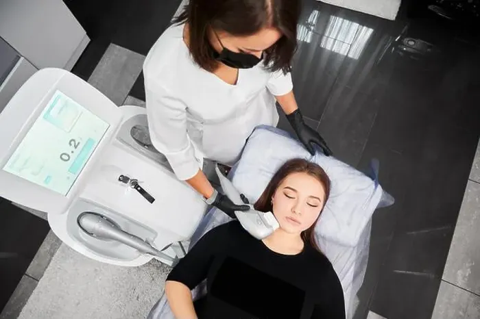 Framed Print : Top view of cosmetologist in medical mask using Ultraformer device while performing face lifting procedure