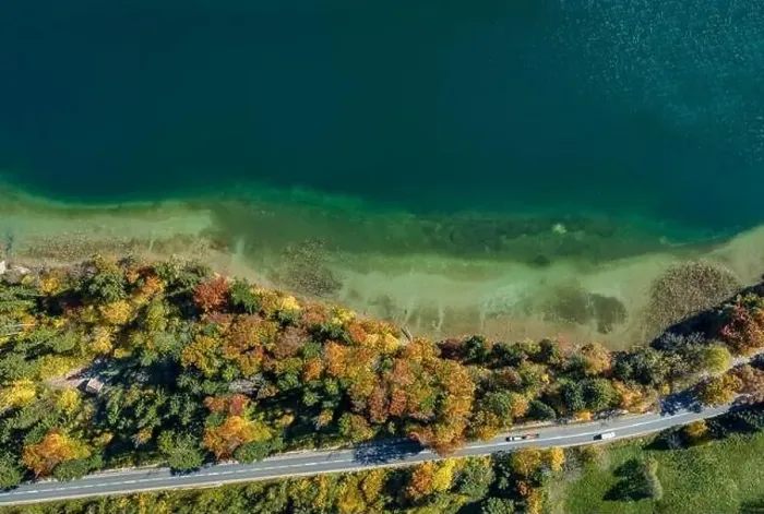 Framed Print : Top view drone shot of a lake with a colorful forest at autumn and a street in the lower section of the photo