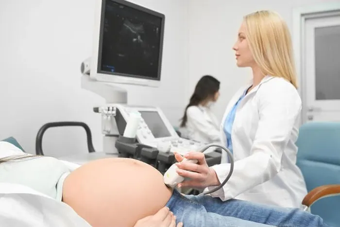 Framed Print : View from side of serious female doctor in white uniform doing ultrasound diagnostic to pregnant woman and looking at screen in clinic Framed Print : View from side of serious female doctor in white uniform doing ultrasound diagnostic to pregnant woman and looking at screen in clinic