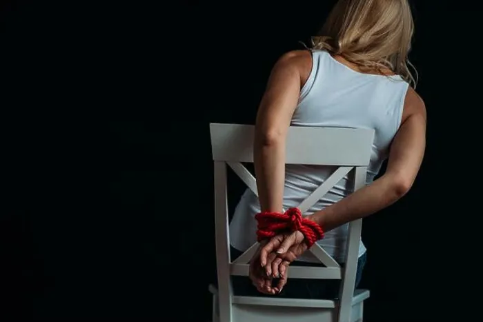 Framed Print : Back view of woman with tied hands sitting on white chair isolated on black Framed Print : Back view of woman with tied hands sitting on white chair isolated on black