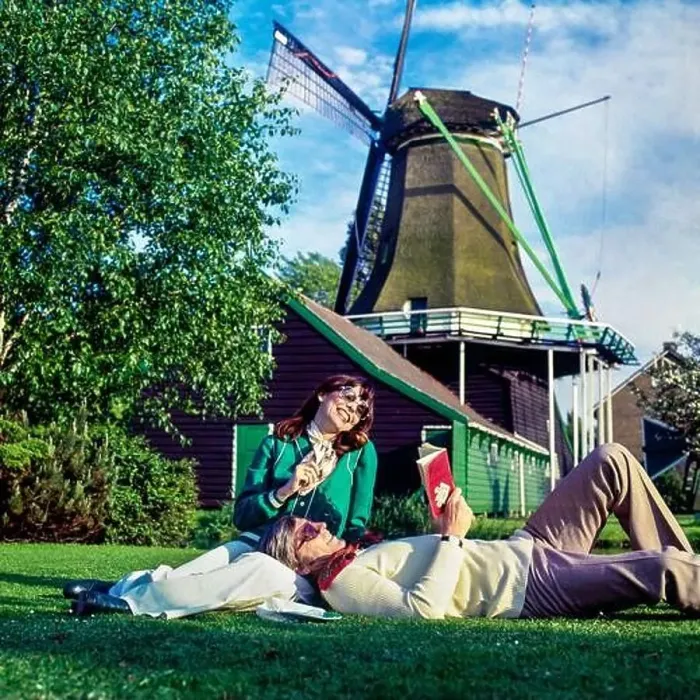 Framed Print : Vintage Netherlands 1970s, couple of middle aged tourists relaxing in meadow beside a windmill, Holland, Europe