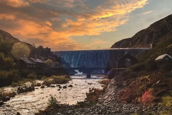 Framed Print : Water flowing over Caban Coch dam in mid Wales with the sun setting behind it