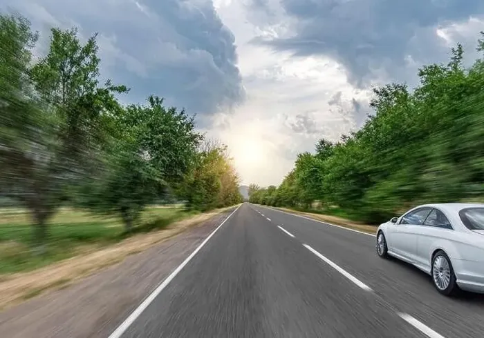 Framed Print : White car drives down the road through the forest along the highway Framed Print : White car drives down the road through the forest along the highway