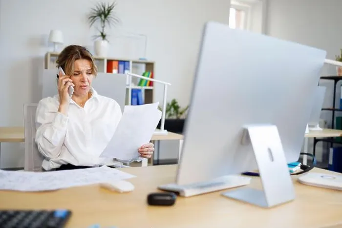 Framed Print : Woman accountant indignantly looks at documents and talks on the smartphone Framed Print : Woman accountant indignantly looks at documents and talks on the smartphone